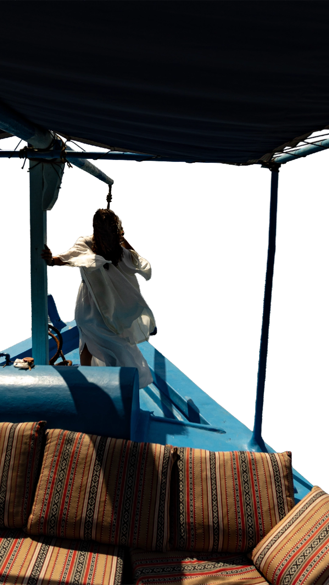 A dramatic shot of a lady dressed in a flowy white outfit, on a dhow, looking in to the horizon