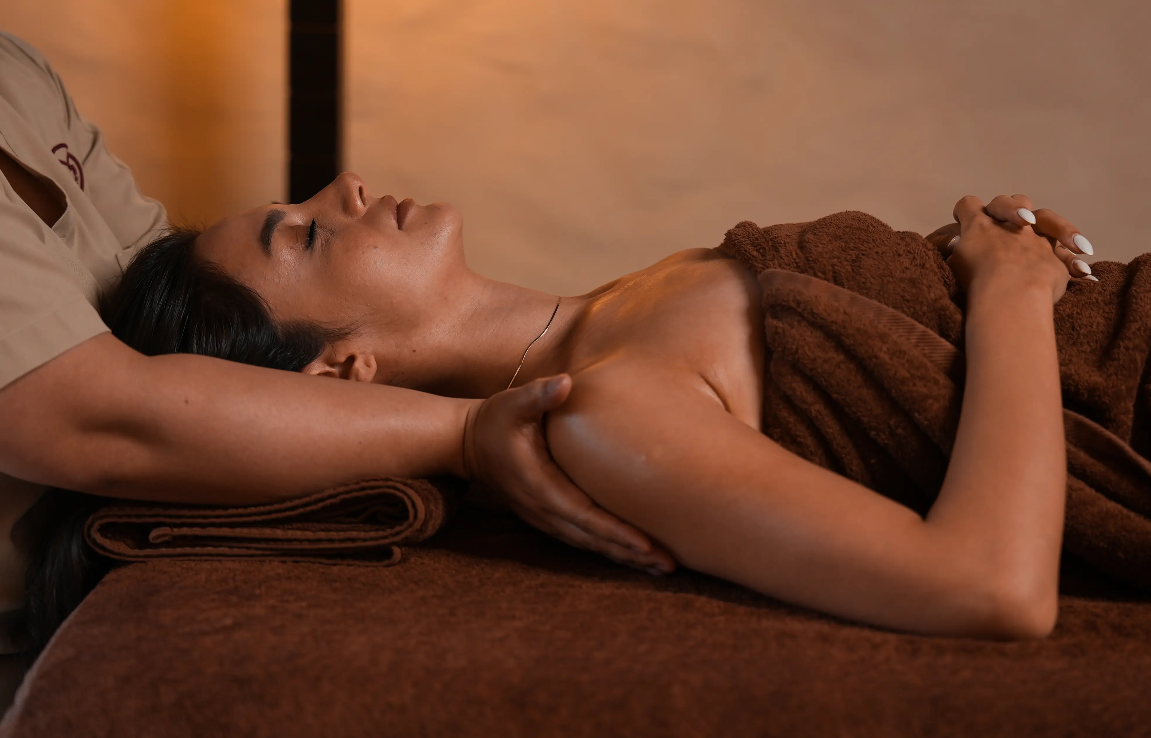 A woman relaxes with her eyes closed while receiving a professional shoulder massage at the hotel spa.