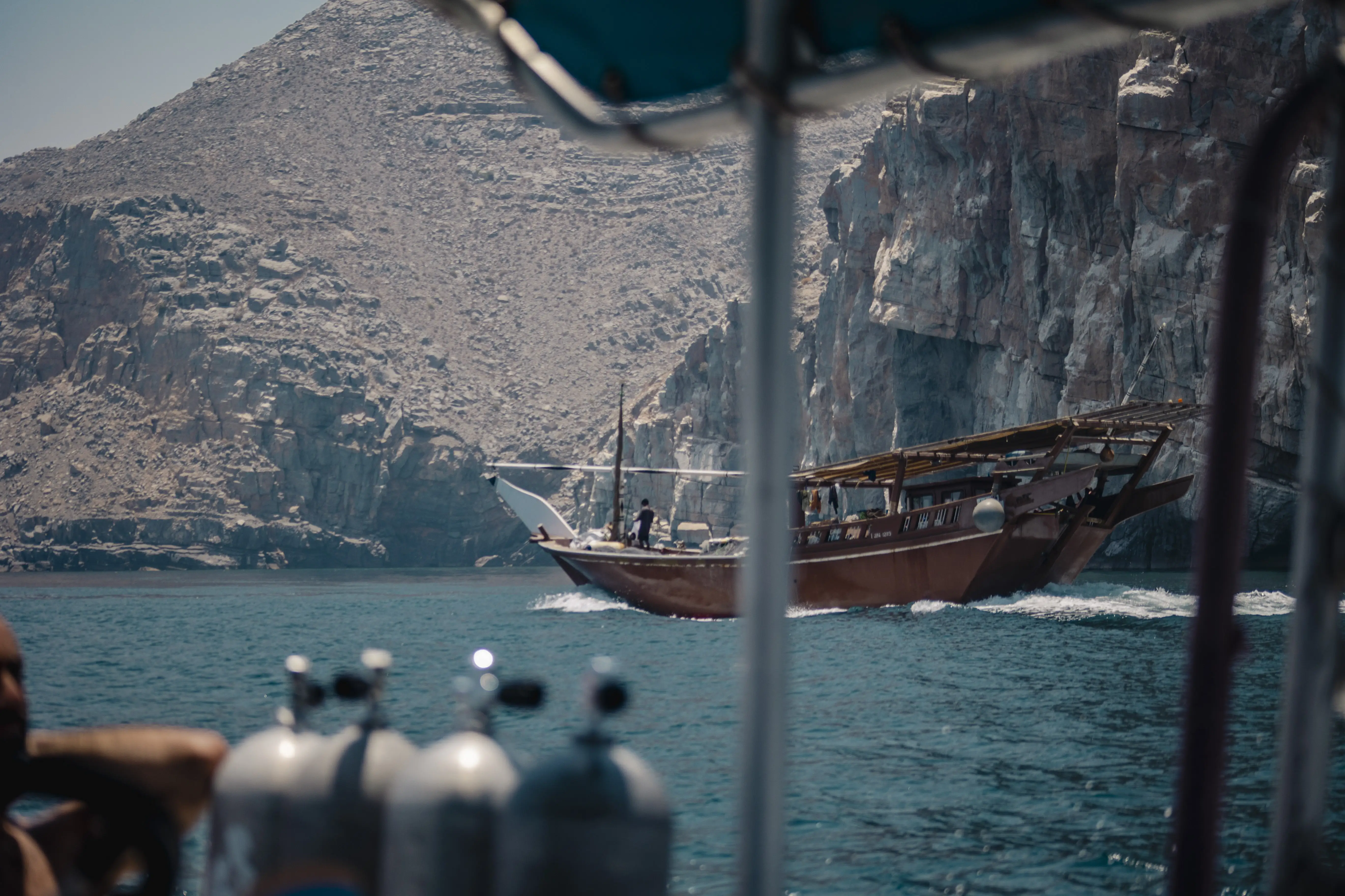 A traditional Omani dhow boat cruises past a dive boat in the Musandam fjords.
