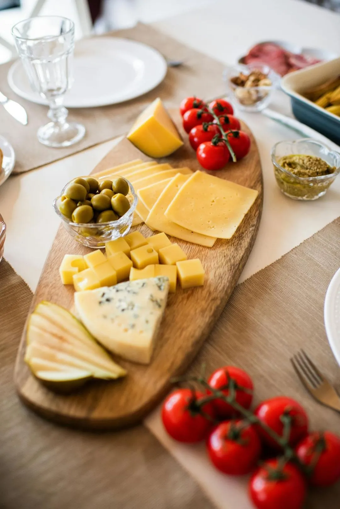 A wooden cutting board with cheese and tomatoes on it.
