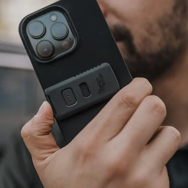 The Stick-On Push-to-Talk Button by Tango Tango on the back of a smartphone as a user listens to PTT.