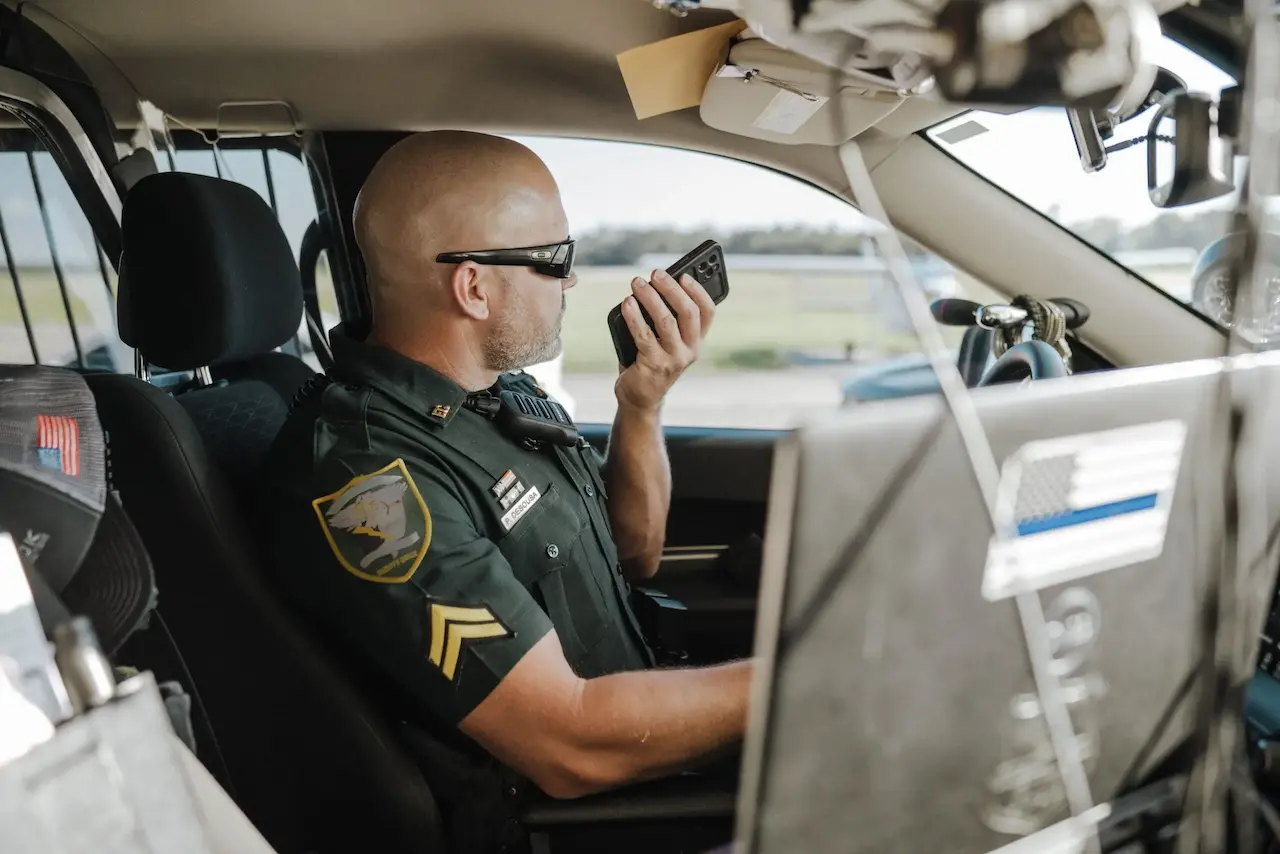 A police officer uses PTT on his smartphone in his patrol car.