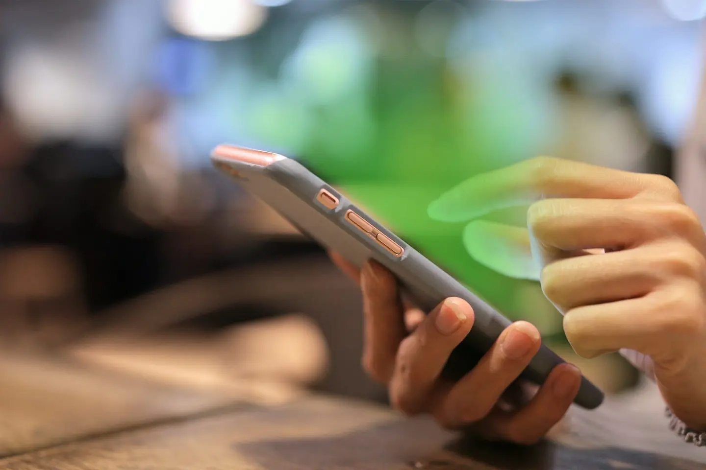 A phone is held in hand with a green glow emitting from the screen