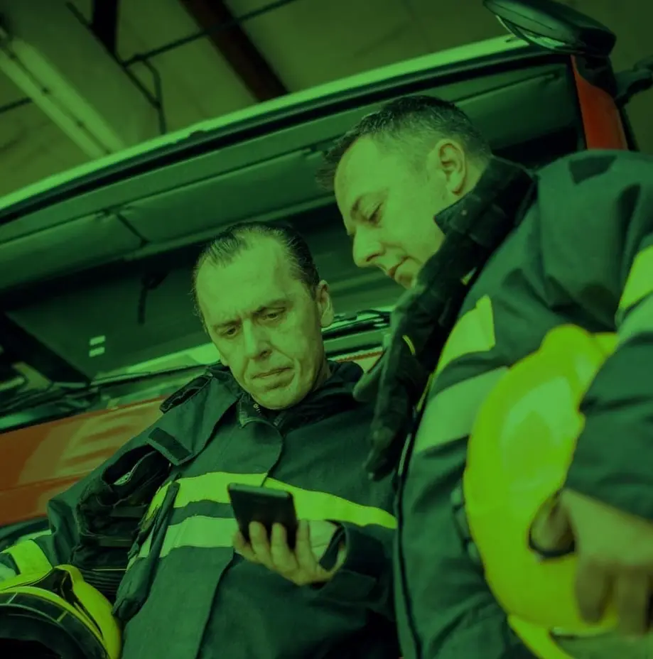 Two firefighters review a CAD Alert. Small size