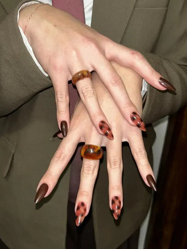 Closeup of brown and black tortoise shell style nails and jewelry