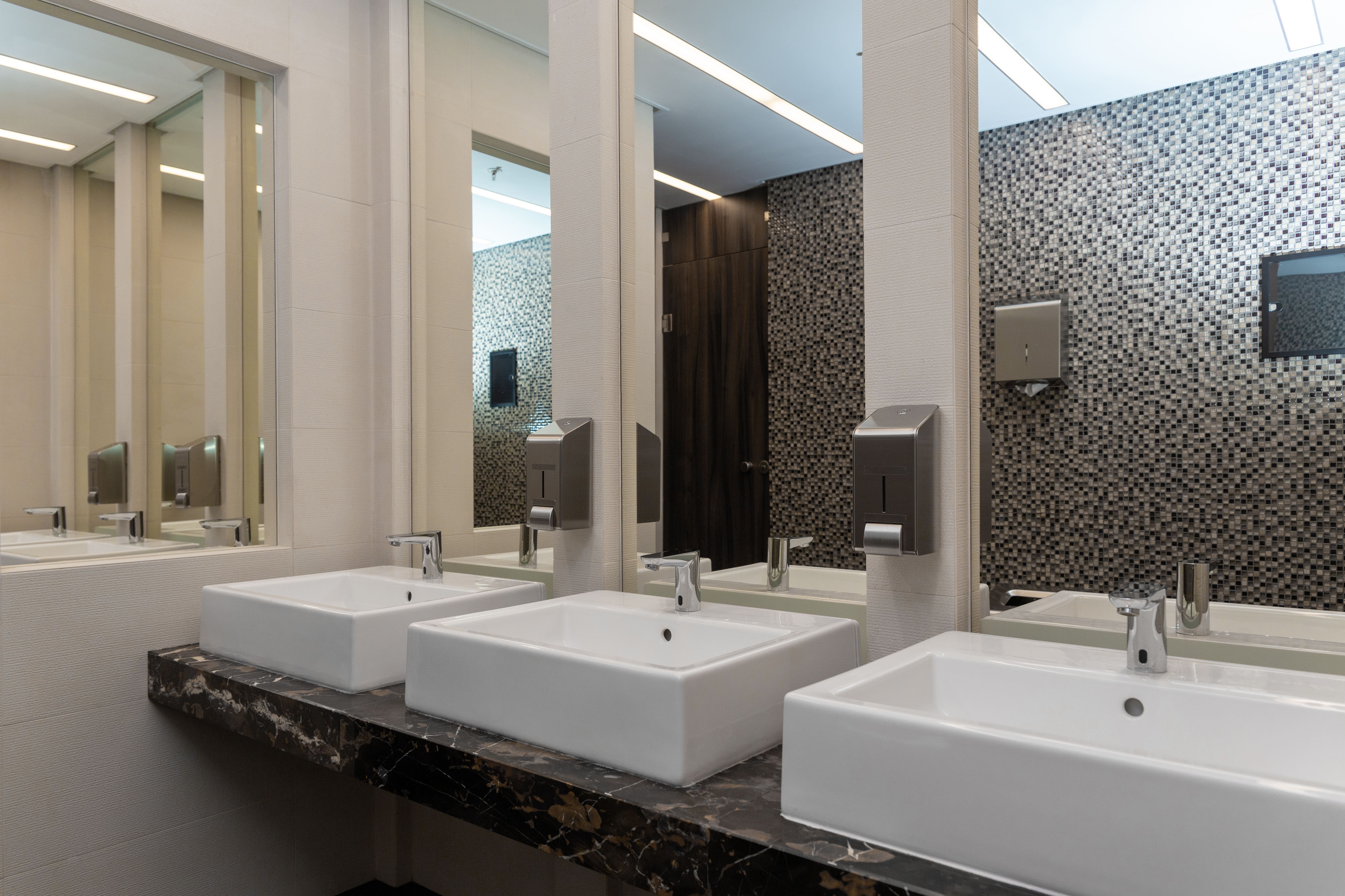 Commercial business bathroom with three sinks in front of three mirrors on the wall
