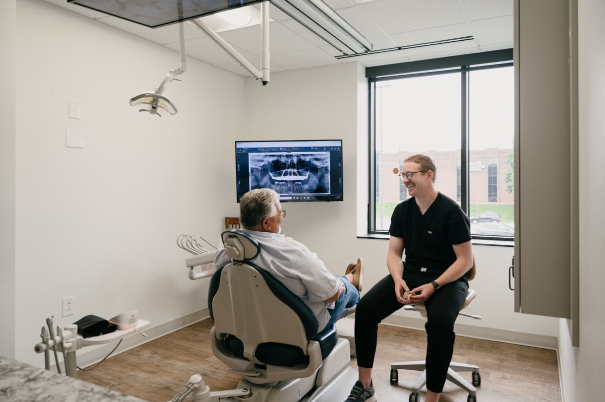 Dentist demonstrating dental implant procedure on patient in clinical treatment room