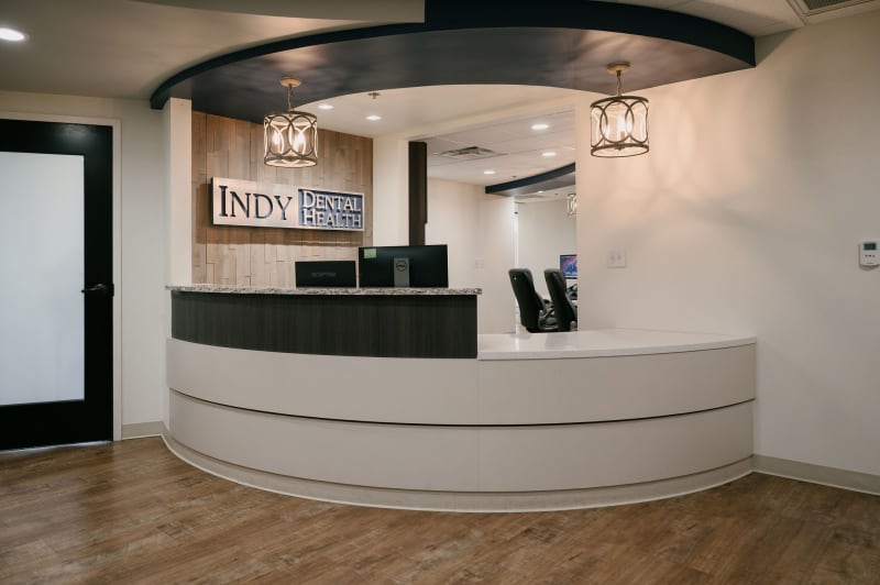 Modern dental practice reception desk with curved white counter and INDY branding