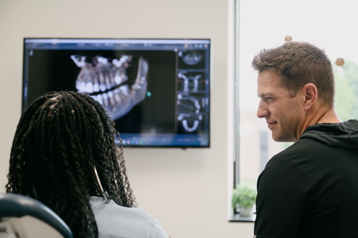 Dentist showing patient digital X-ray on monitor during consultation