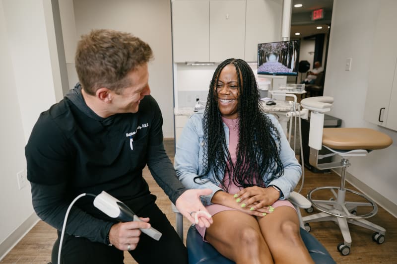 Male dentist consulting with female patient in treatment chair