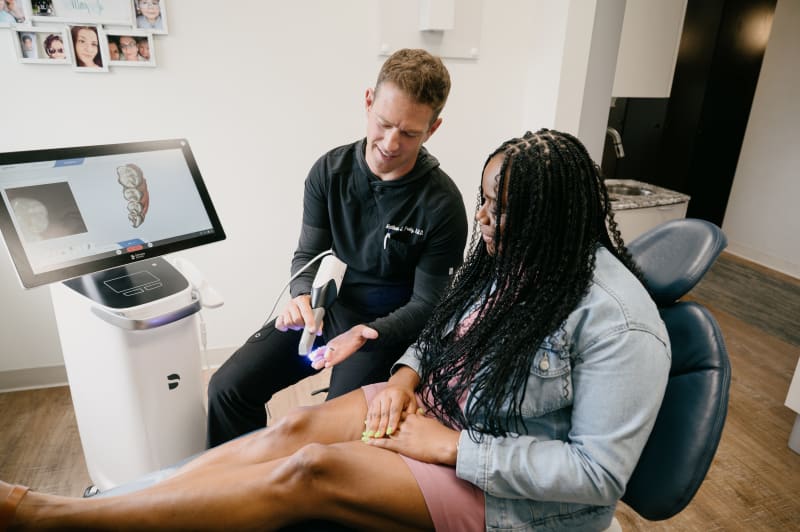 Dentist examining patient in clinical treatment chair with intraoral camera