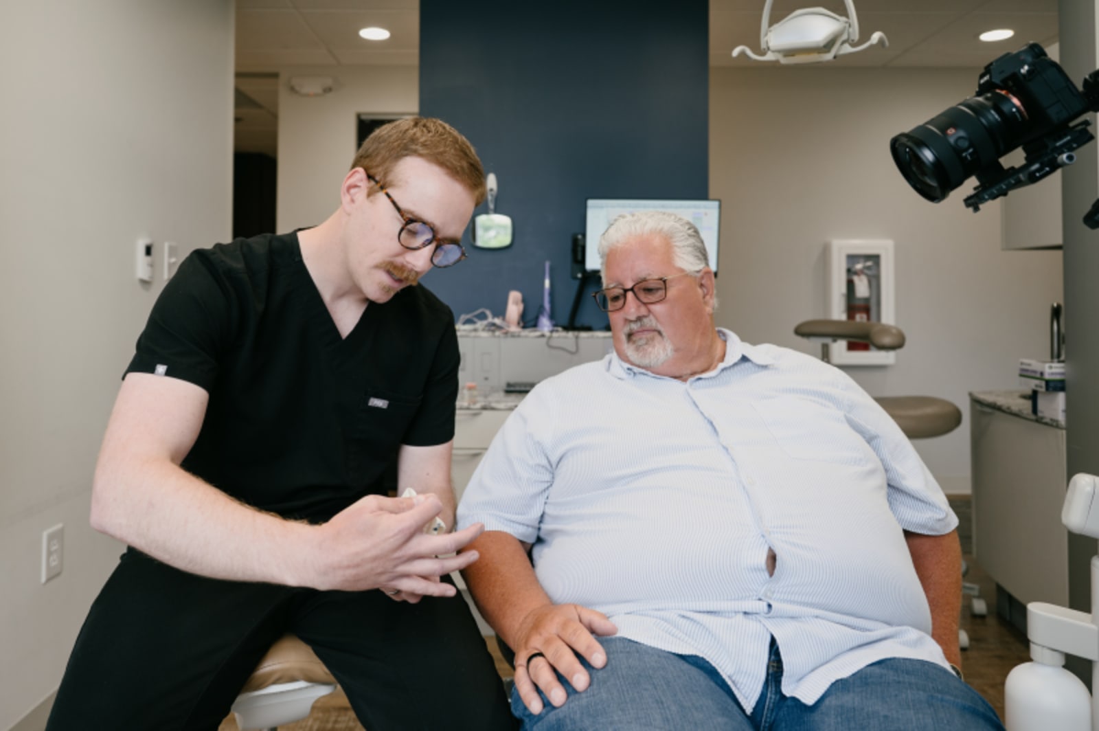 Dentist discussing digital X-ray imaging and treatment plan with patient in clinical setting