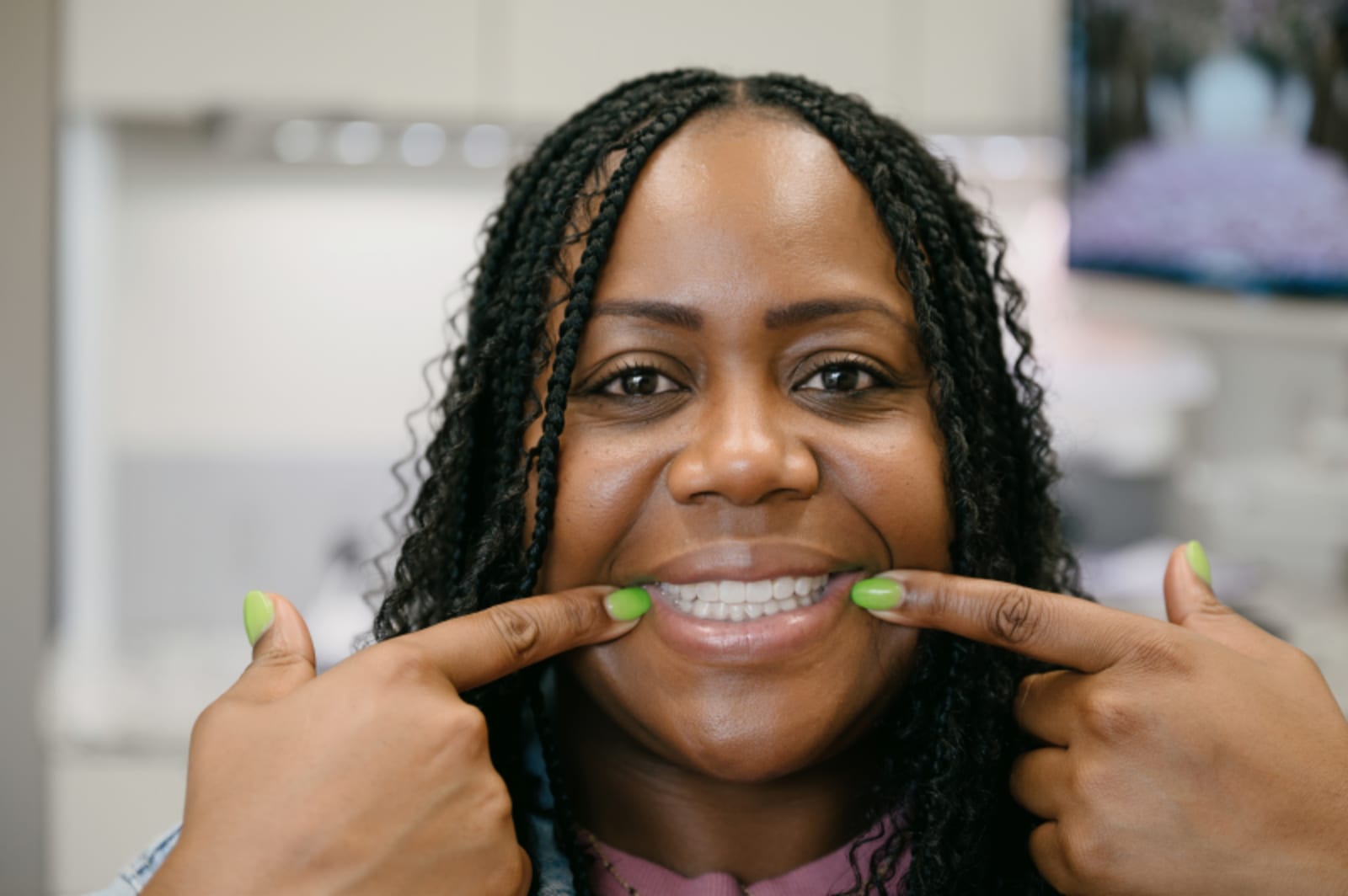 Patient smiling and pointing to their teeth showing results of orthodontic treatment