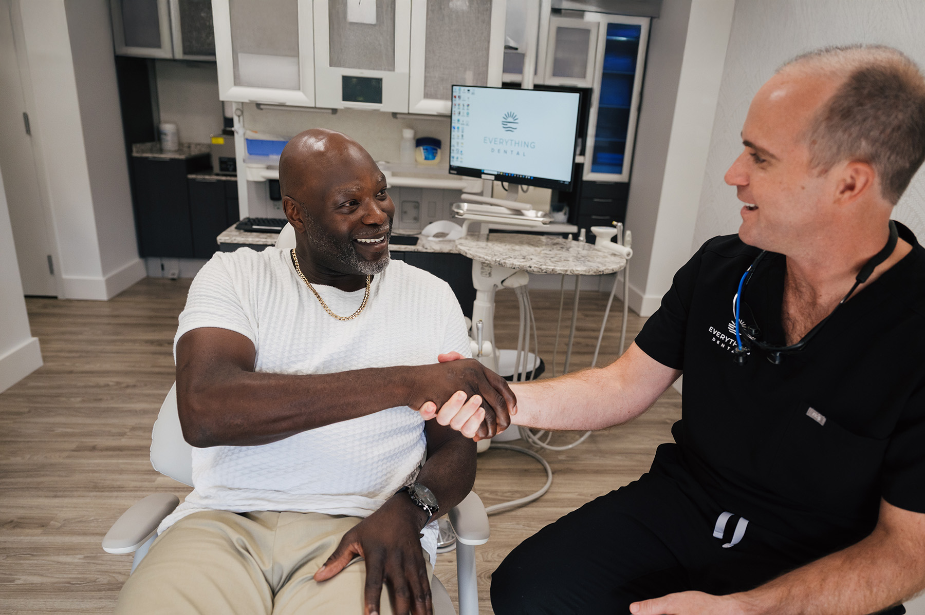 Smiling male dental patient shaking hands with dentist in a dental office.