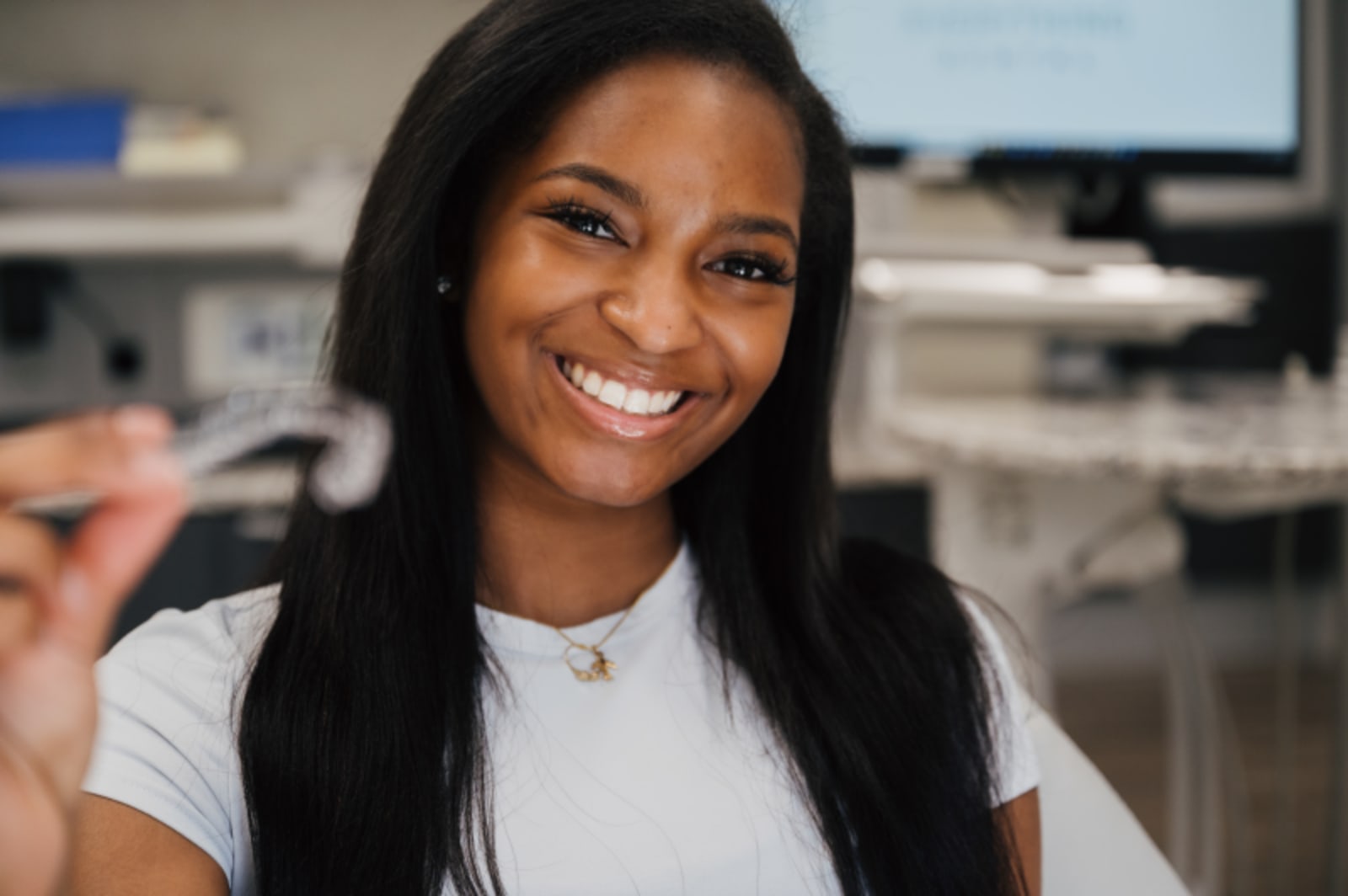 Young woman smiling and pointing to her teeth, showing healthy smile