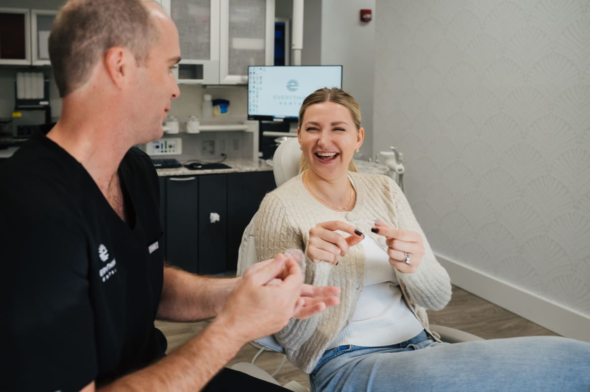 Dentist showing patient a clear retainer, discussing treatment options