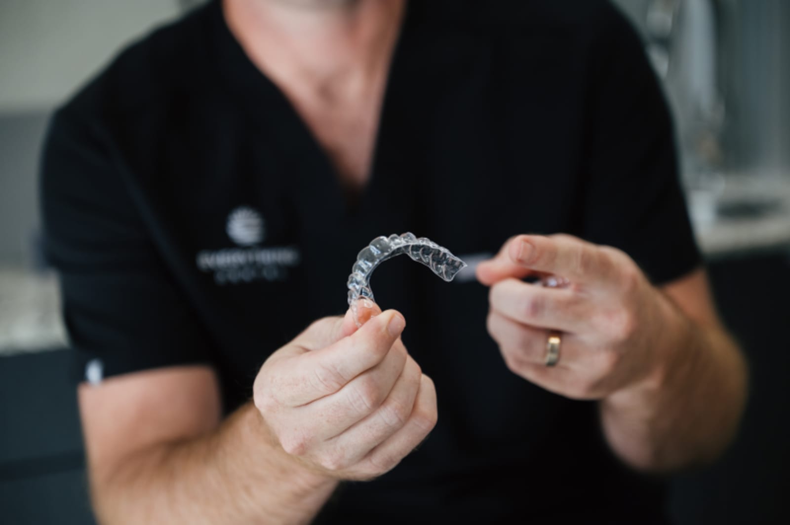 Dentist holding and explaining clear aligner tray to patient
