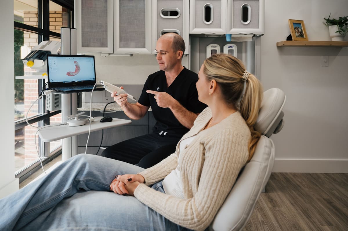 Dentist discussing clear aligner treatment plan with patient in clinical setting