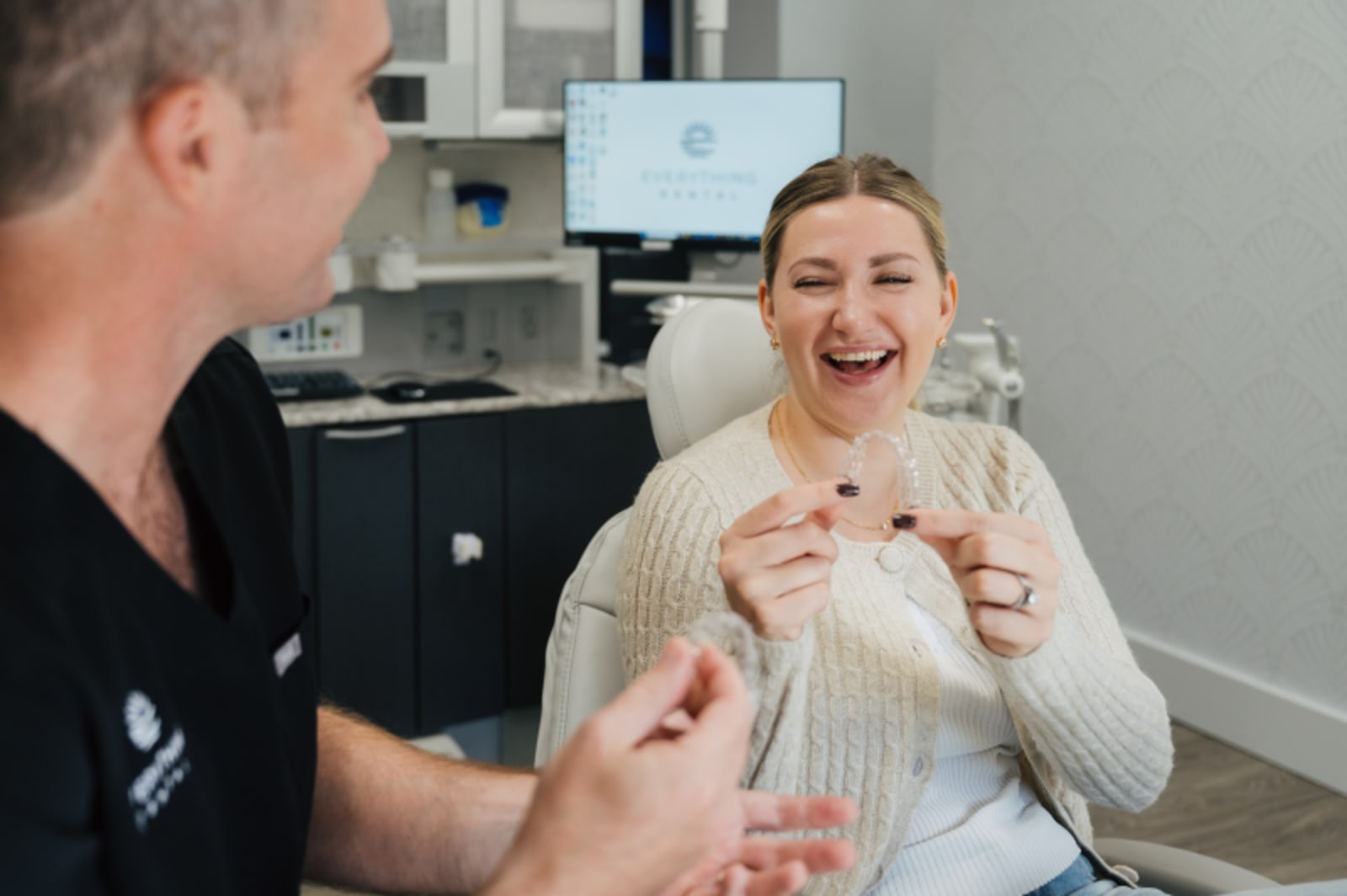 Dentist showing patient how to insert and remove clear aligner trays
