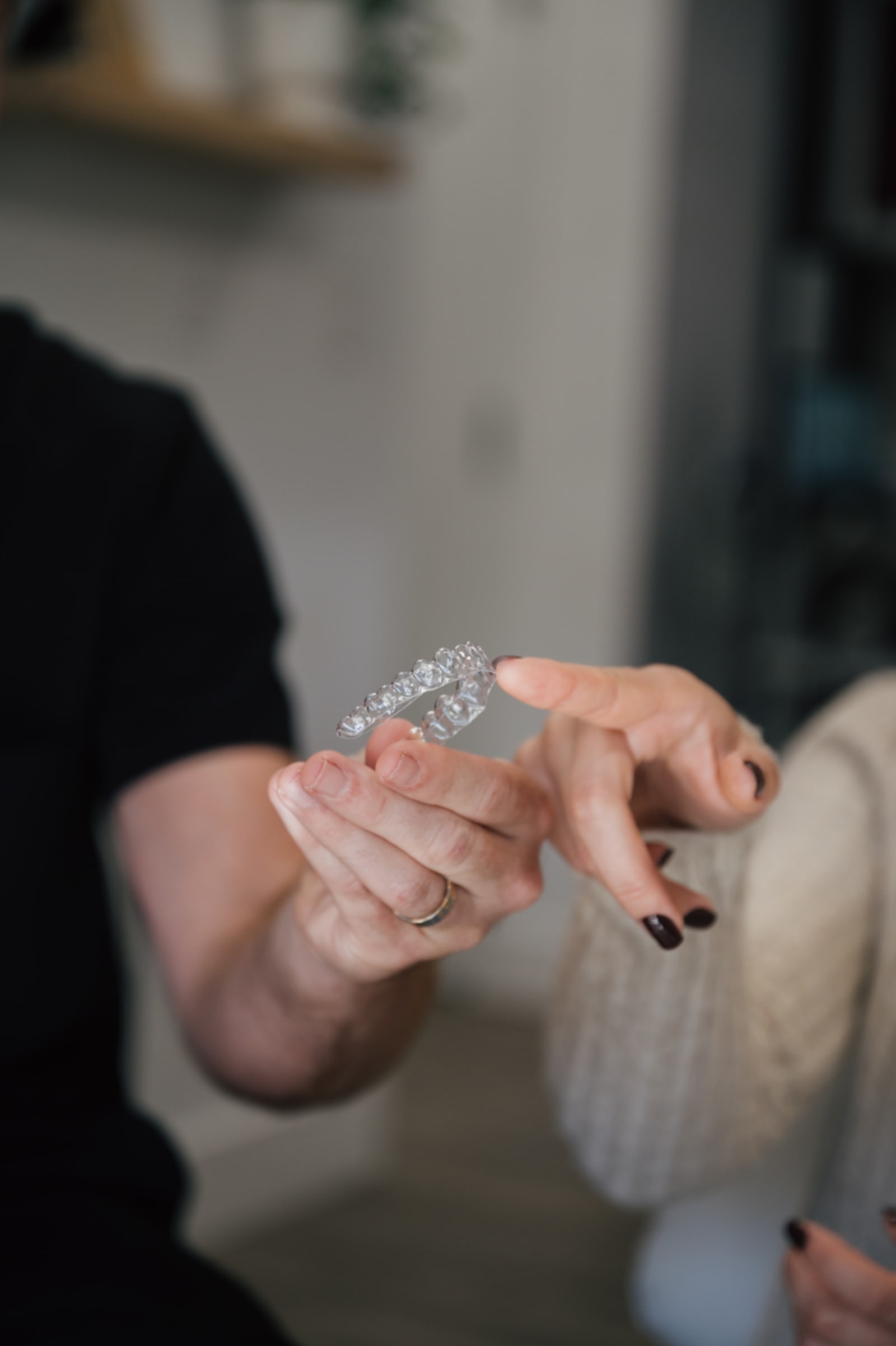 Person holding a clear aligner tray in their hand, showing the transparent orthodontic device.