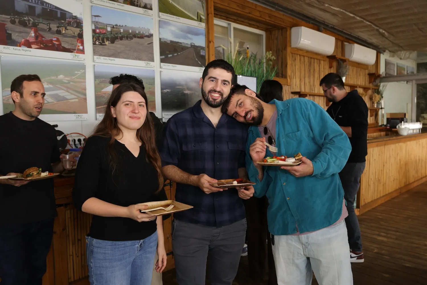 A group of people standing next to each other holding plates of food.