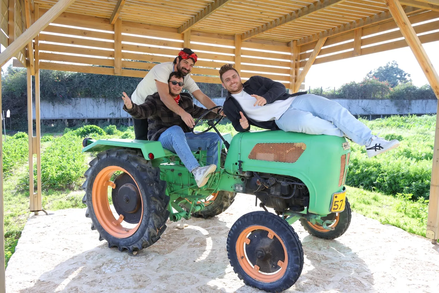 A group of people riding on the back of a green tractor.