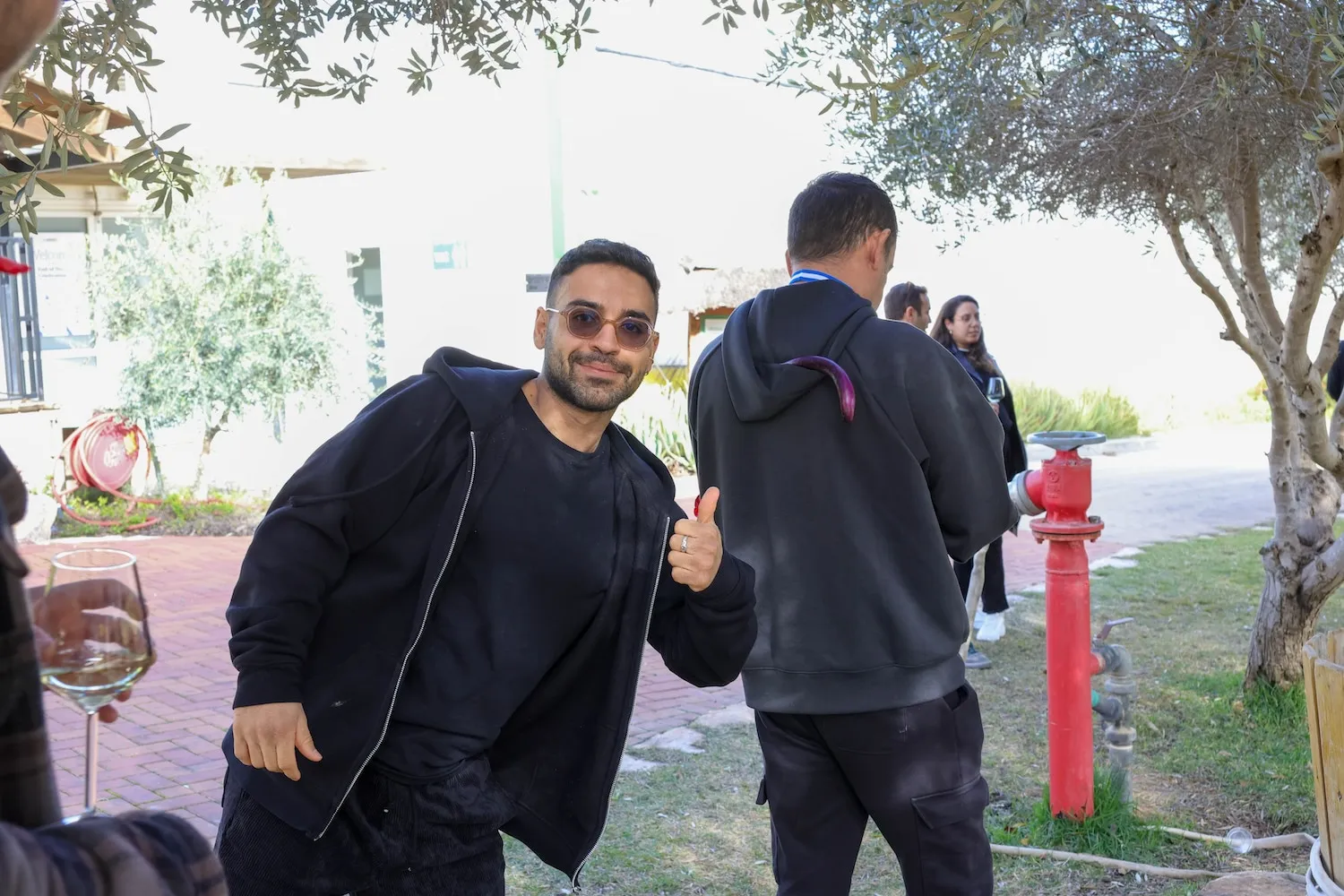 A man giving a thumbs up while standing next to a fire hydrant.