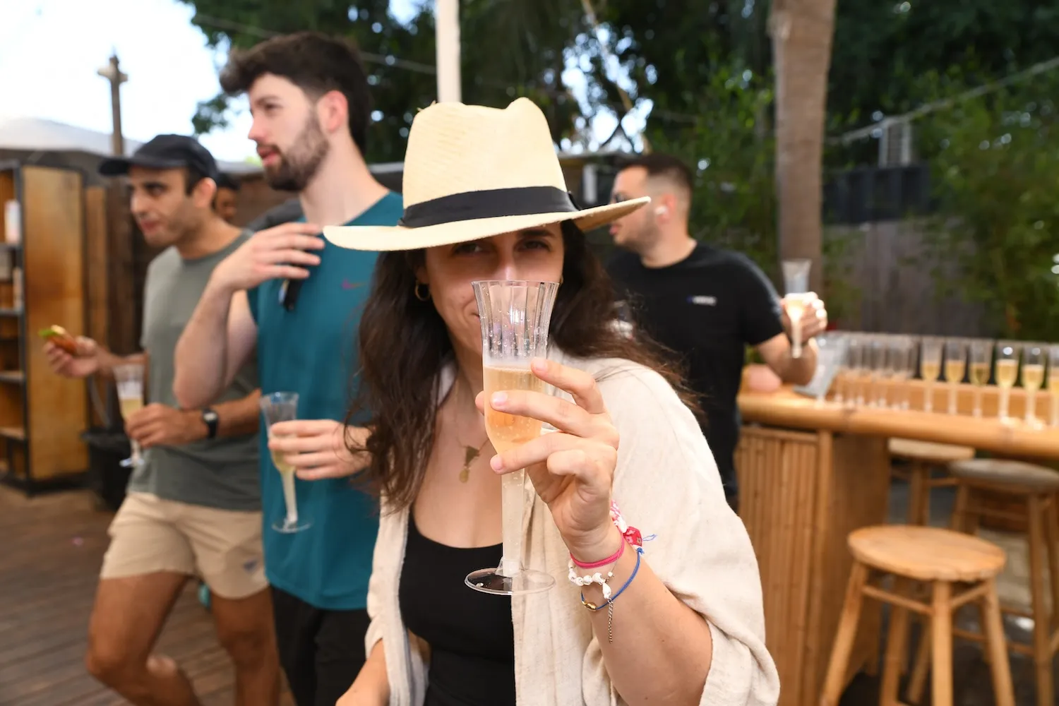 A woman in a hat holding a glass of wine.