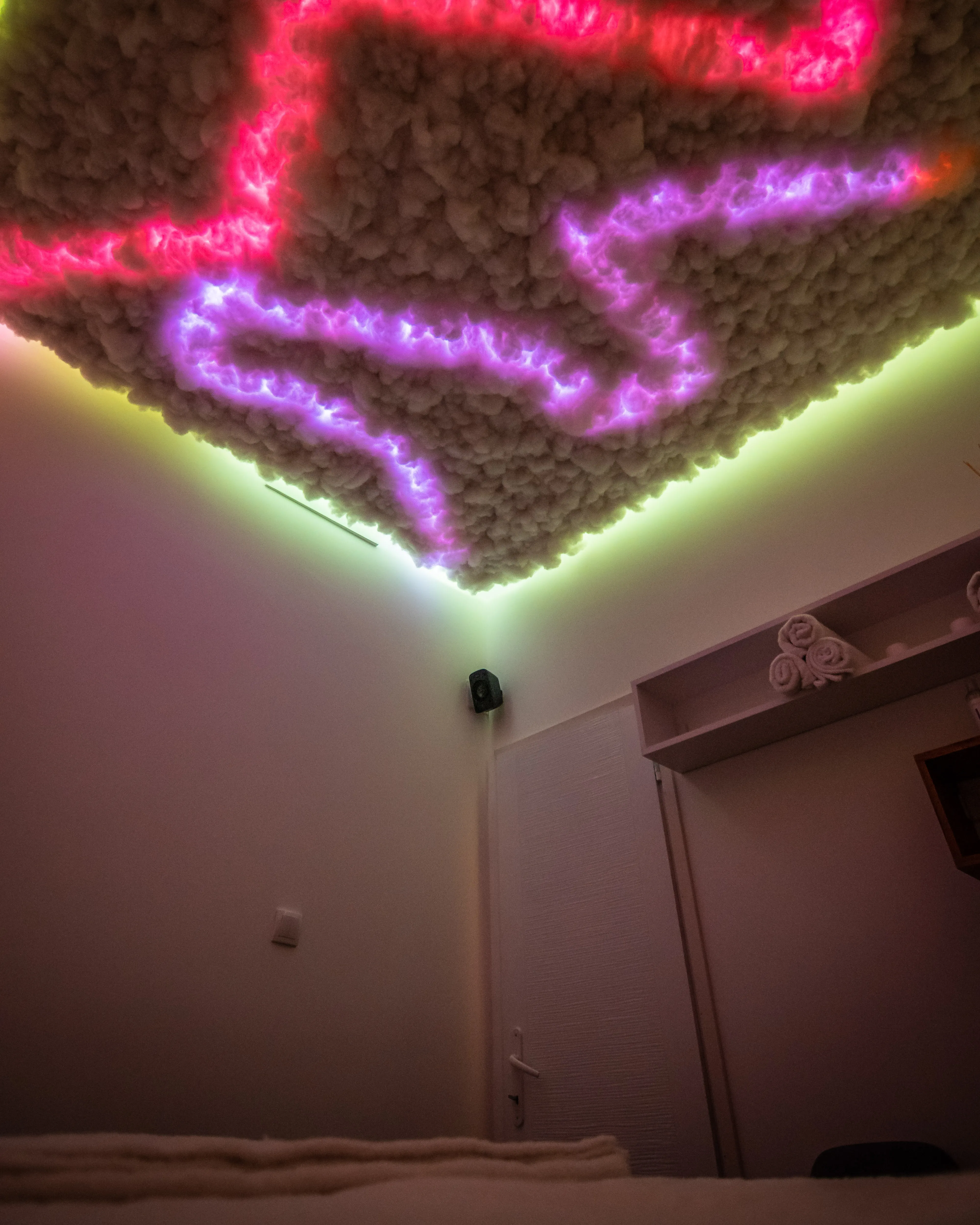 Dekorativni plafon sa roze i crvenim LED svetlima koji izgleda kao oblaci u sobi za masažu - Runway Massage.