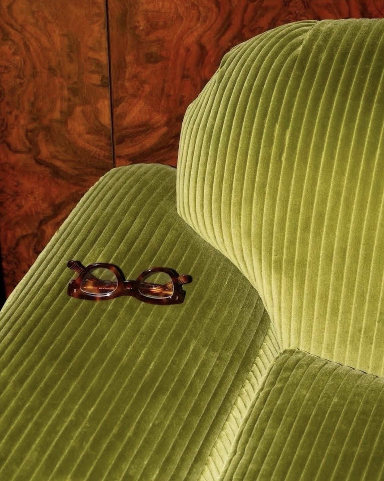 Green office chair in front of modern wood paneling with trendy glasses on the chair arm
