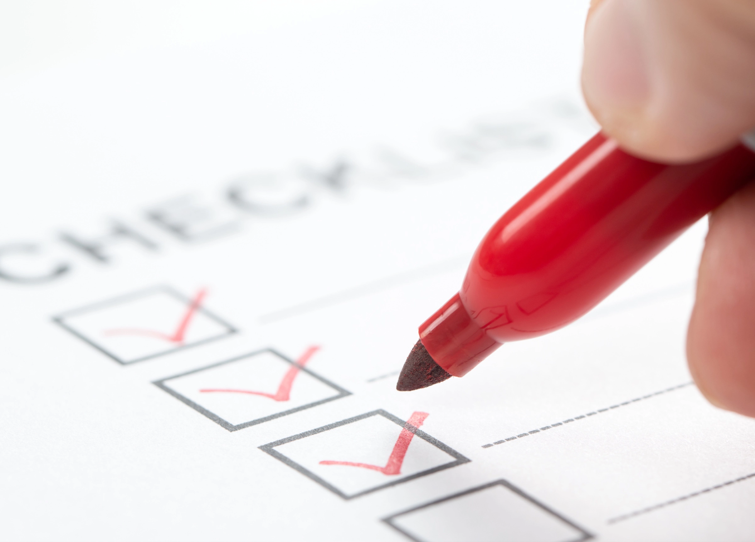 An image of a person ticking boxes on a form using a red marker pen