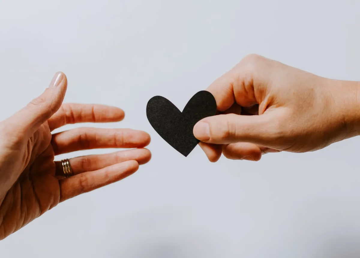 Closeup of hands passing a paper heart between them