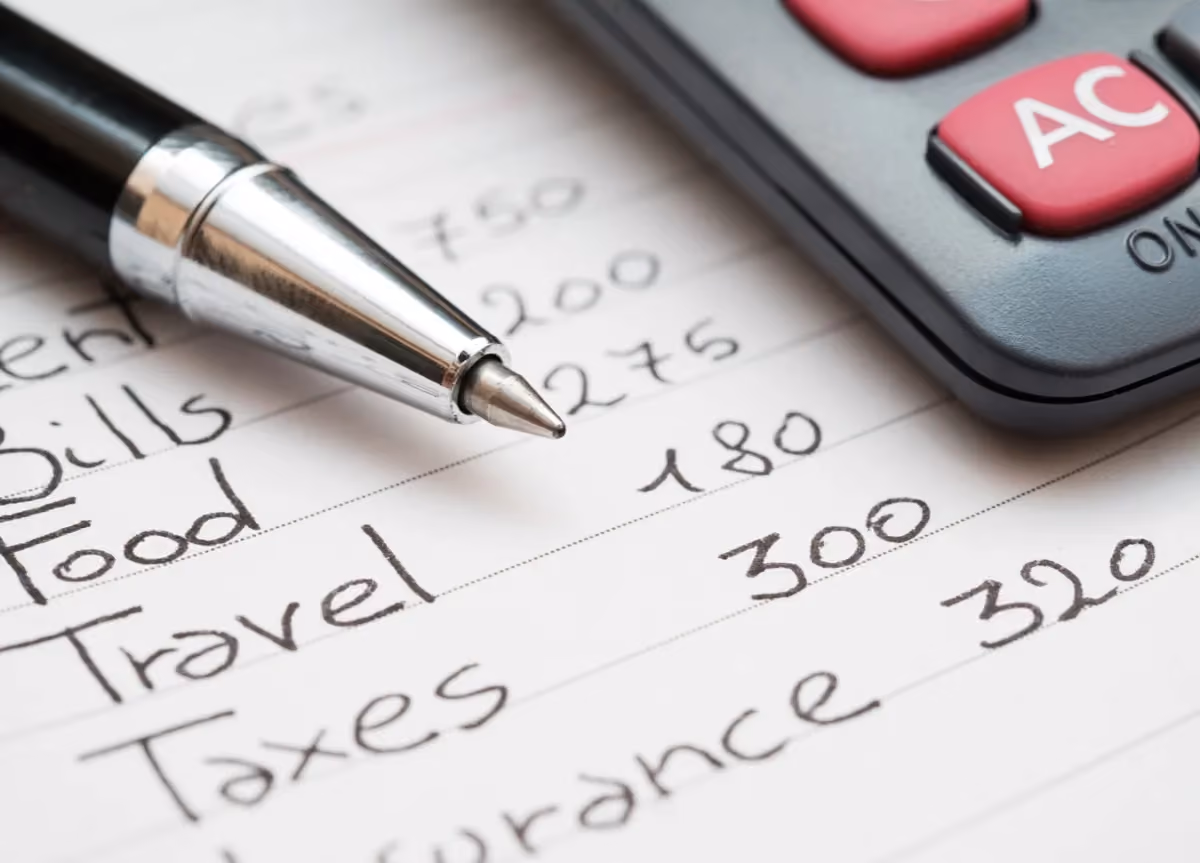 A close up of a pen and calculator on a paper with come calculations written by hand