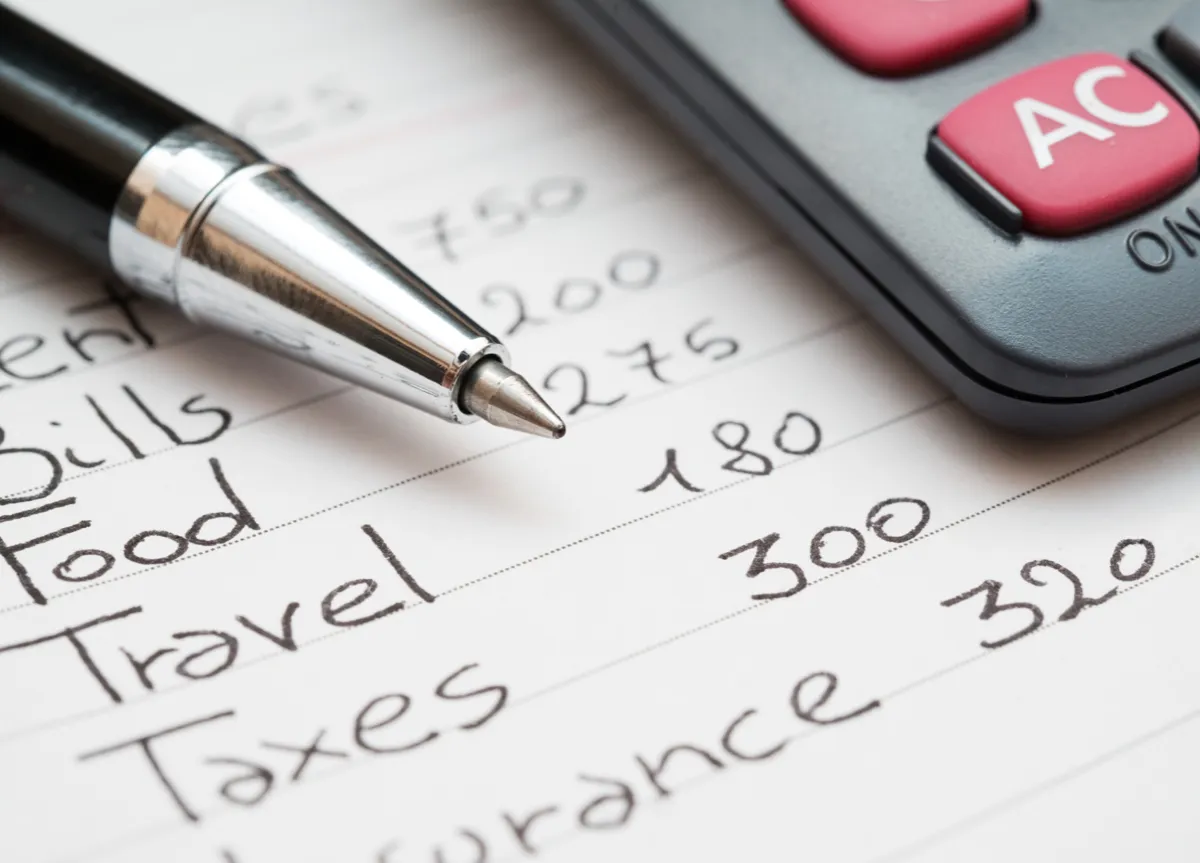 A close up of a pen and calculator on a paper with come calculations written by hand