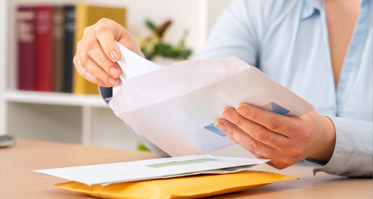 A person placing a letter into an envelope