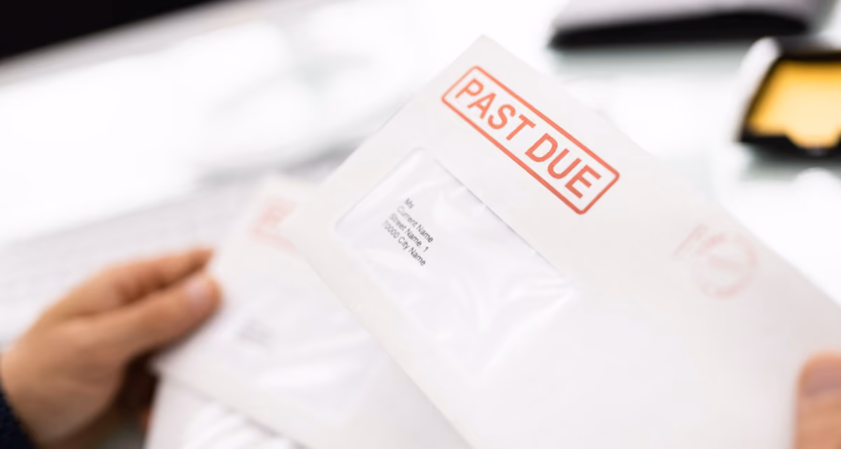 Hands holding an envelope with a red Past Due stamp on it