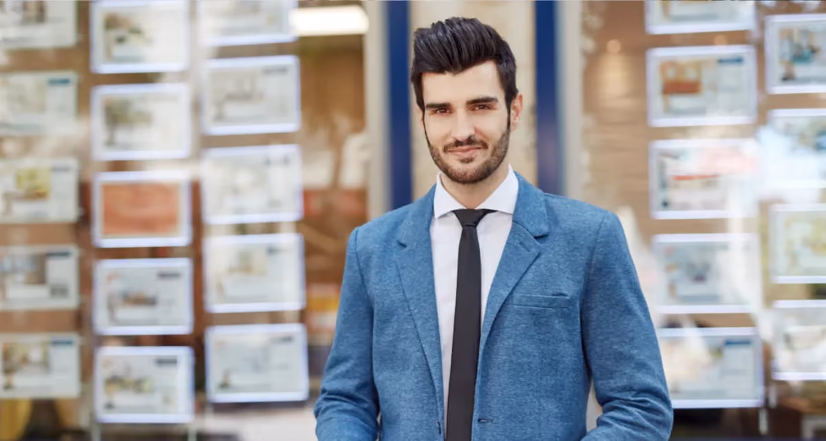 A man wearing a suit standing in front of a rental agency window