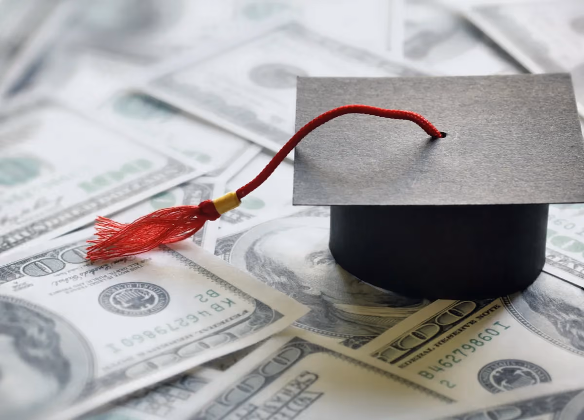 Graduation cap on top of a pile of $100 US bills