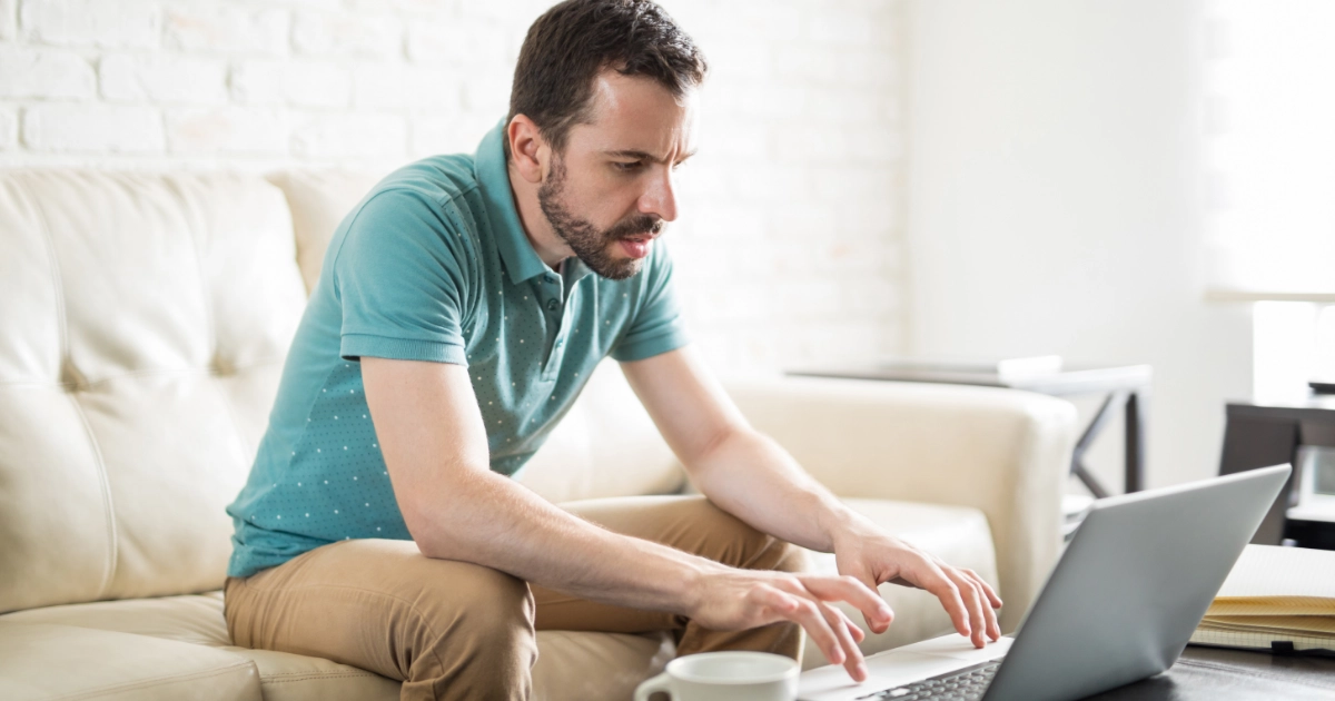A man using a laptop while sitting on a sofa