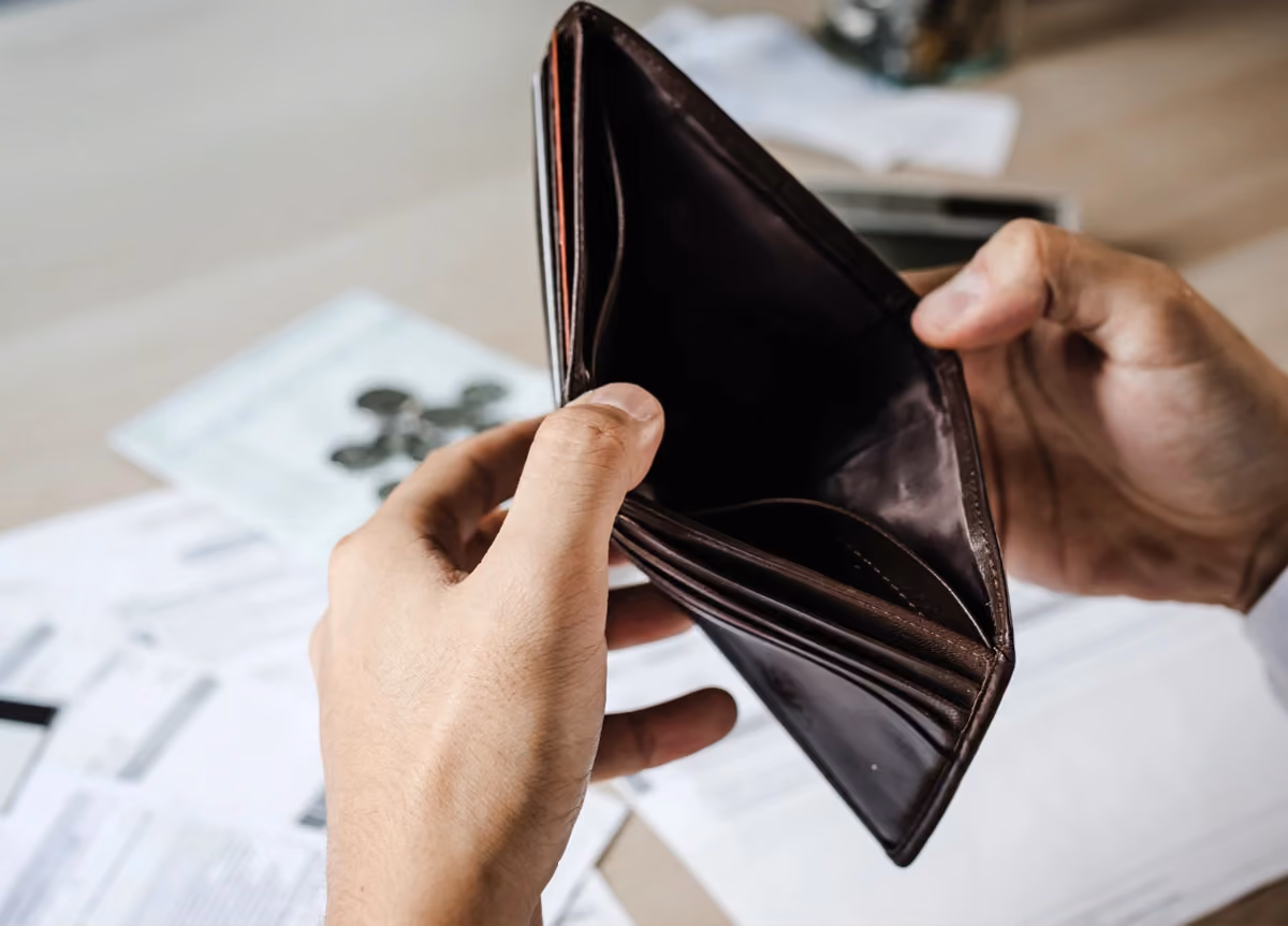 Man holds empty wallet with documents in background