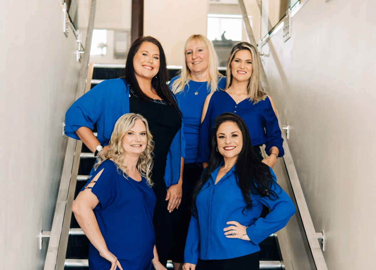 Group photo of the five women of Valor Property Management wearing blue, standing on stairs, smiling for the camera.