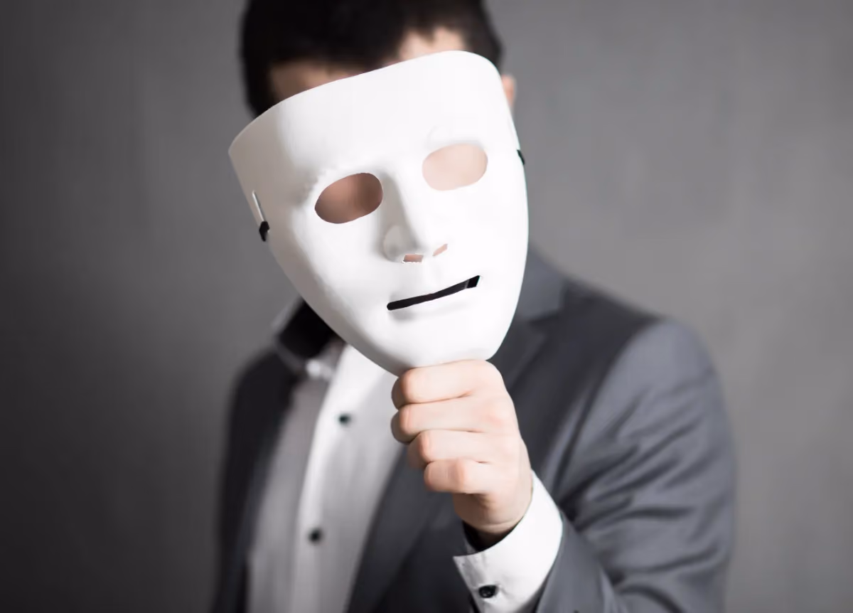 Man hides face behind white mask