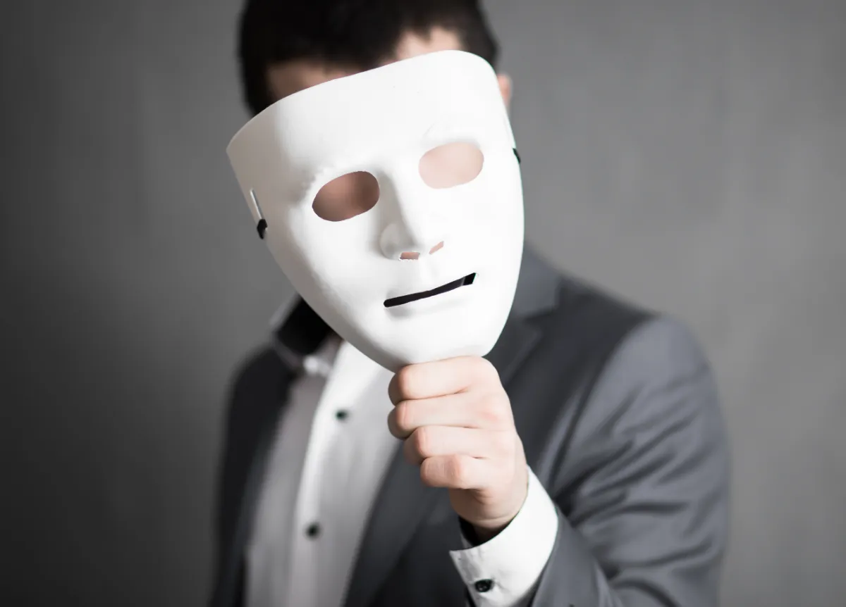 Man hides face behind white mask