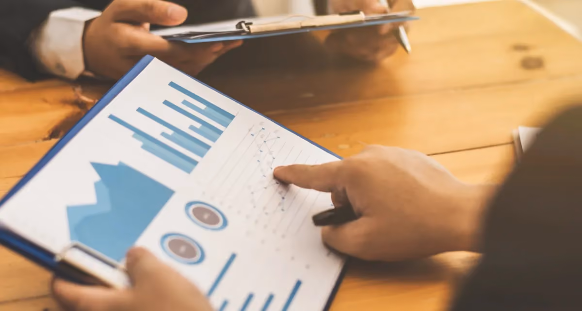 A pair of hands holding and pointing at a graph