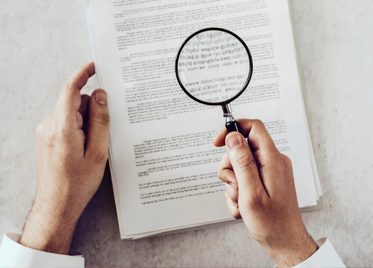 Man inspecting important document with magnifying glass