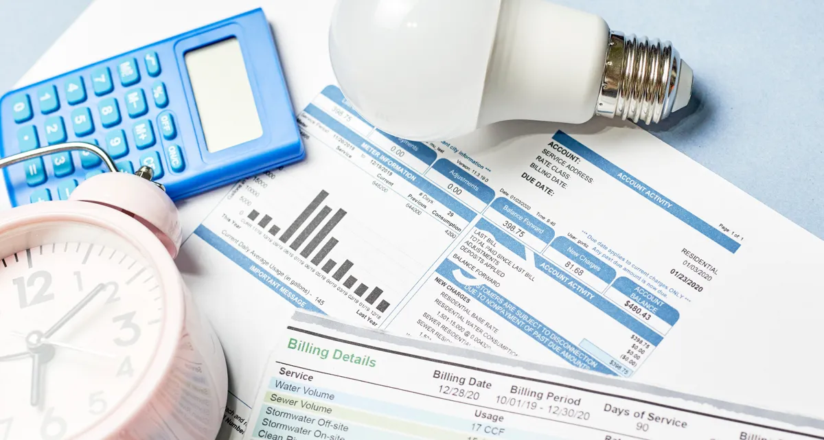 Printed energy bills with a lightbulb, calculator and alarm c