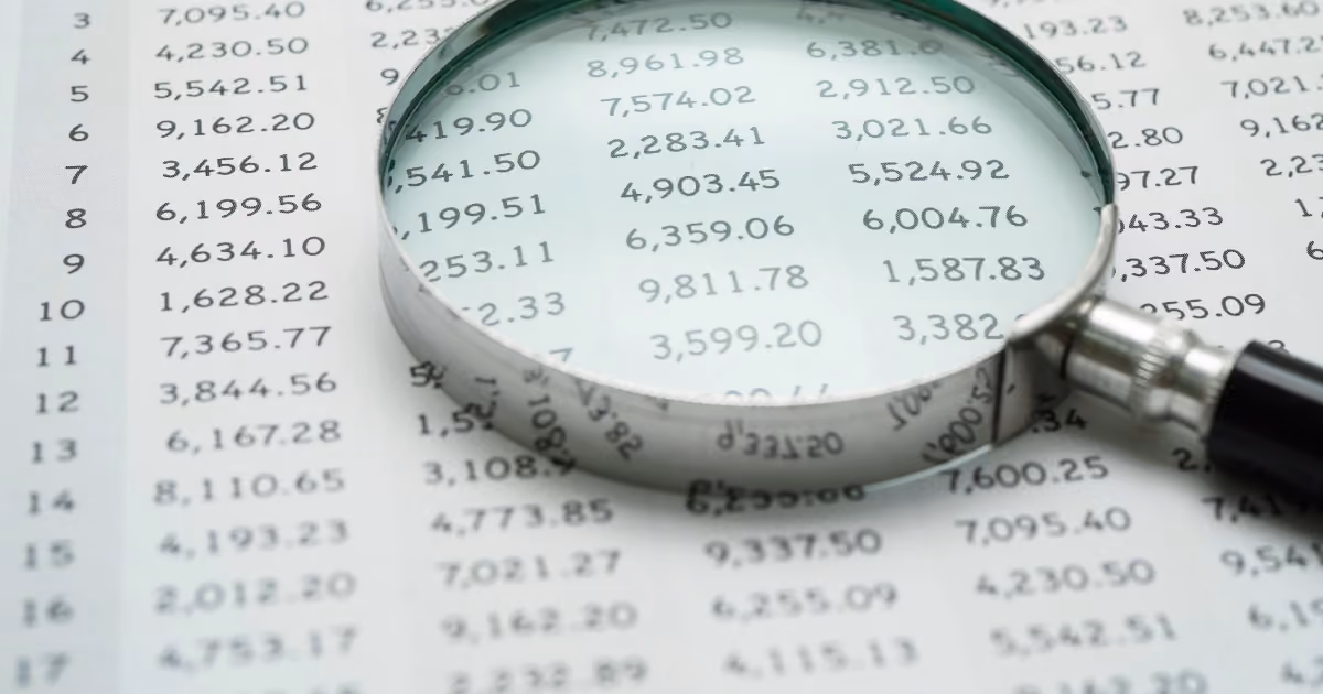 A magnifying glass on top of a spreadsheet