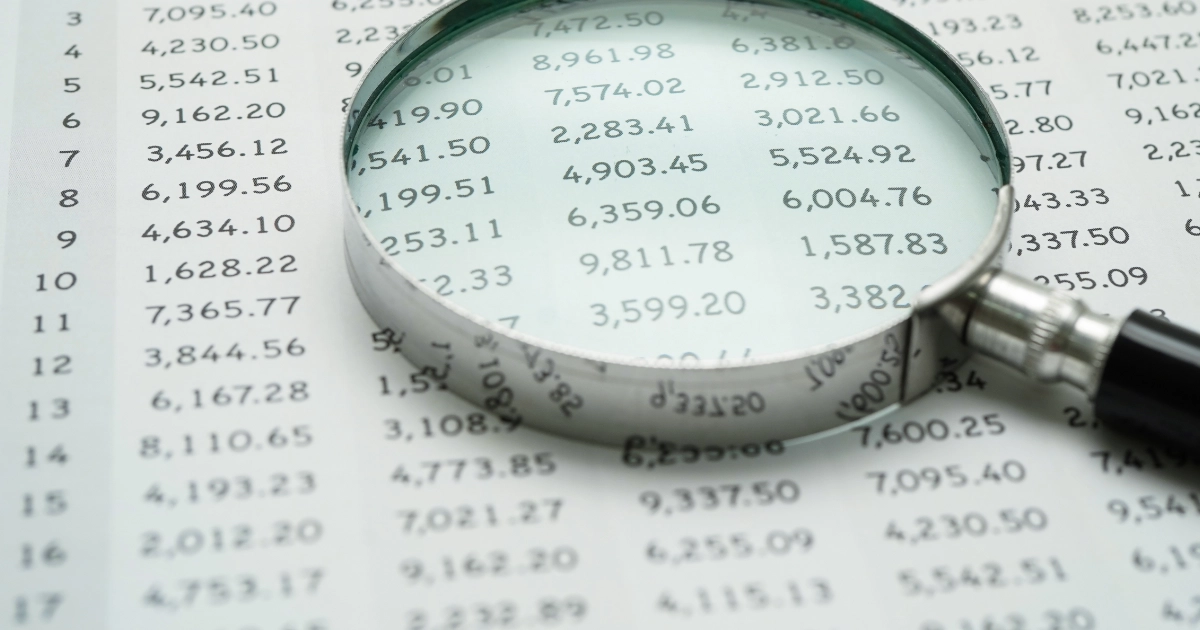 A magnifying glass on top of a spreadsheet