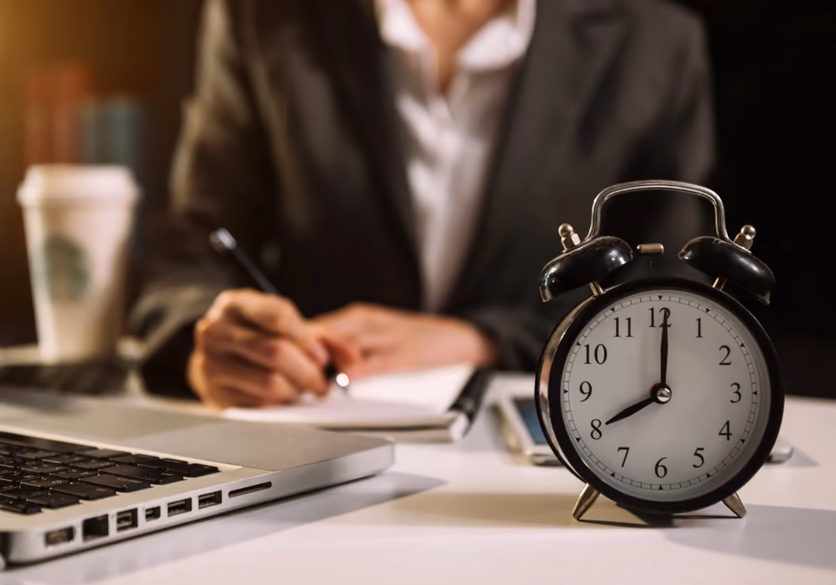 Businessman working at desk with alarm clock in foreground