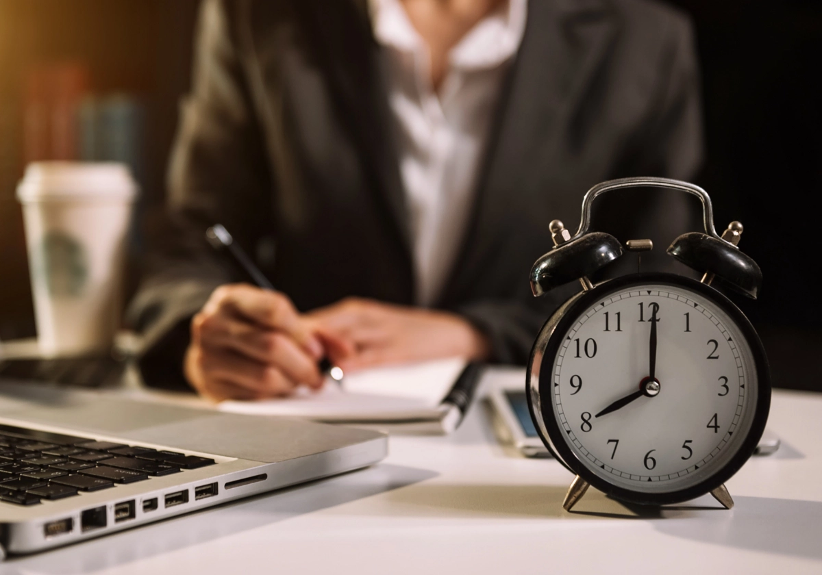 Businessman working at desk with alarm clock in foreground